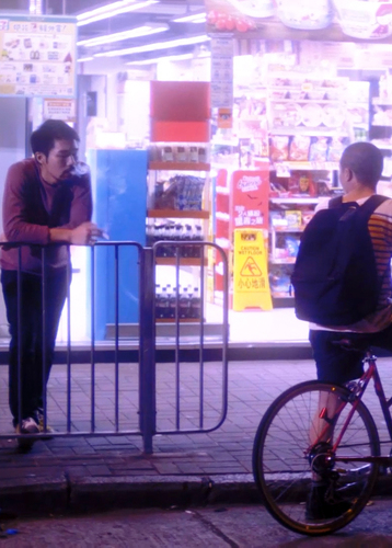 Needs translation: Filmstill aus I miss you when I see you, ein Mann sieht einem anderen mit Fahrrad auf der nächtlichen Straße an